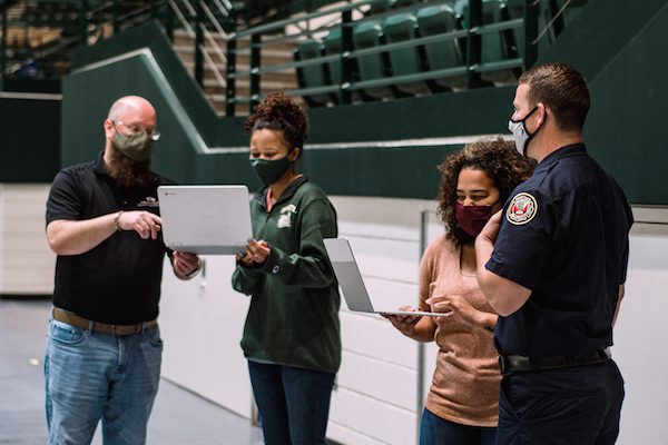 Darien Woods (second from right) and Lauren Hairston (second from left) confer with Emergency Preparedness Coordinator Kevin Martin (left) and firefighter David Hodnett during an on-campus COVID-19 vaccine clinic. 